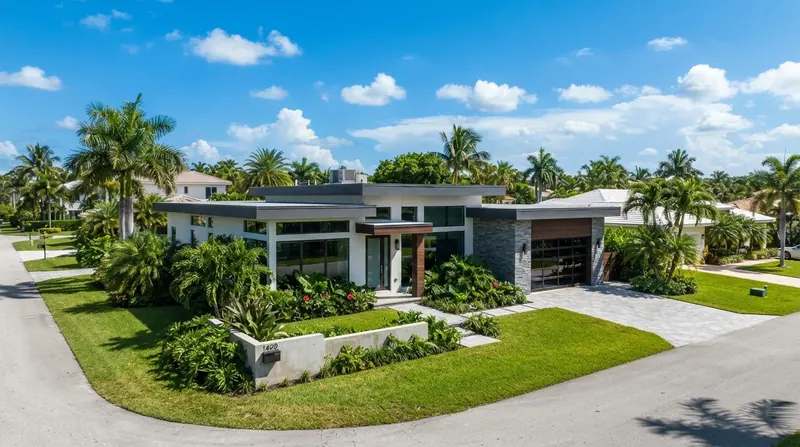 Modern flat-roof home with deep overhangs surrounded by palms